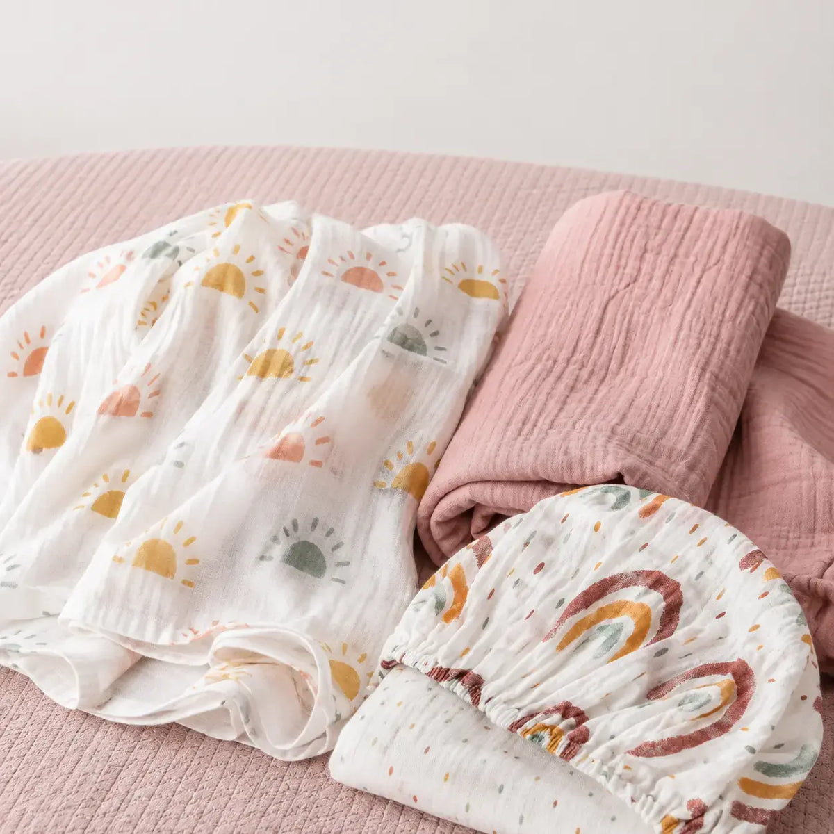 Peony Haze muslin swaddle and Sunbeam fitted cot sheet flat lay with minimalist sun print, birds eye view - Honey & Sage