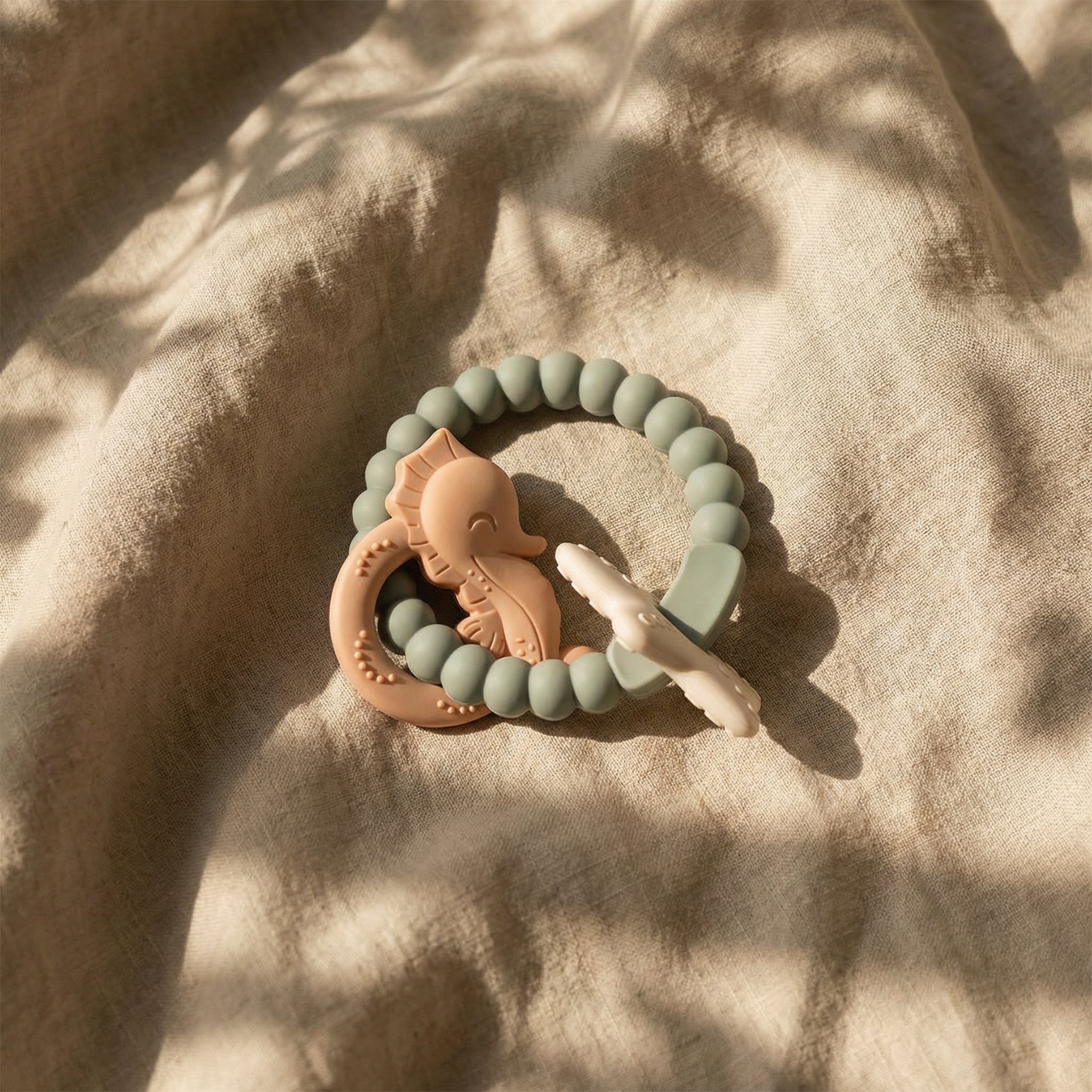 Green and peachtoned baby teether flat lay minimal background
