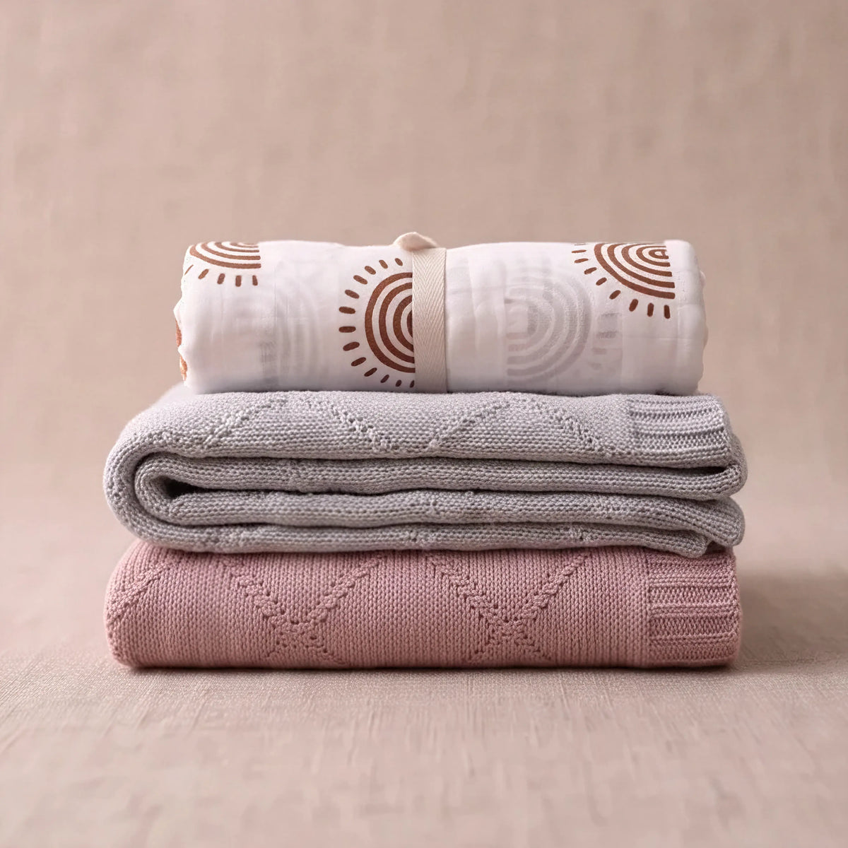 Deluxe knit blanket and swaddle bundle, folded stack of muslin swaddle and diamond knit blankets