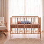 Cocoa fitted baby cot sheet on oak cot with baby swaddled in Lunar muslin swaddle - Honey & Sage