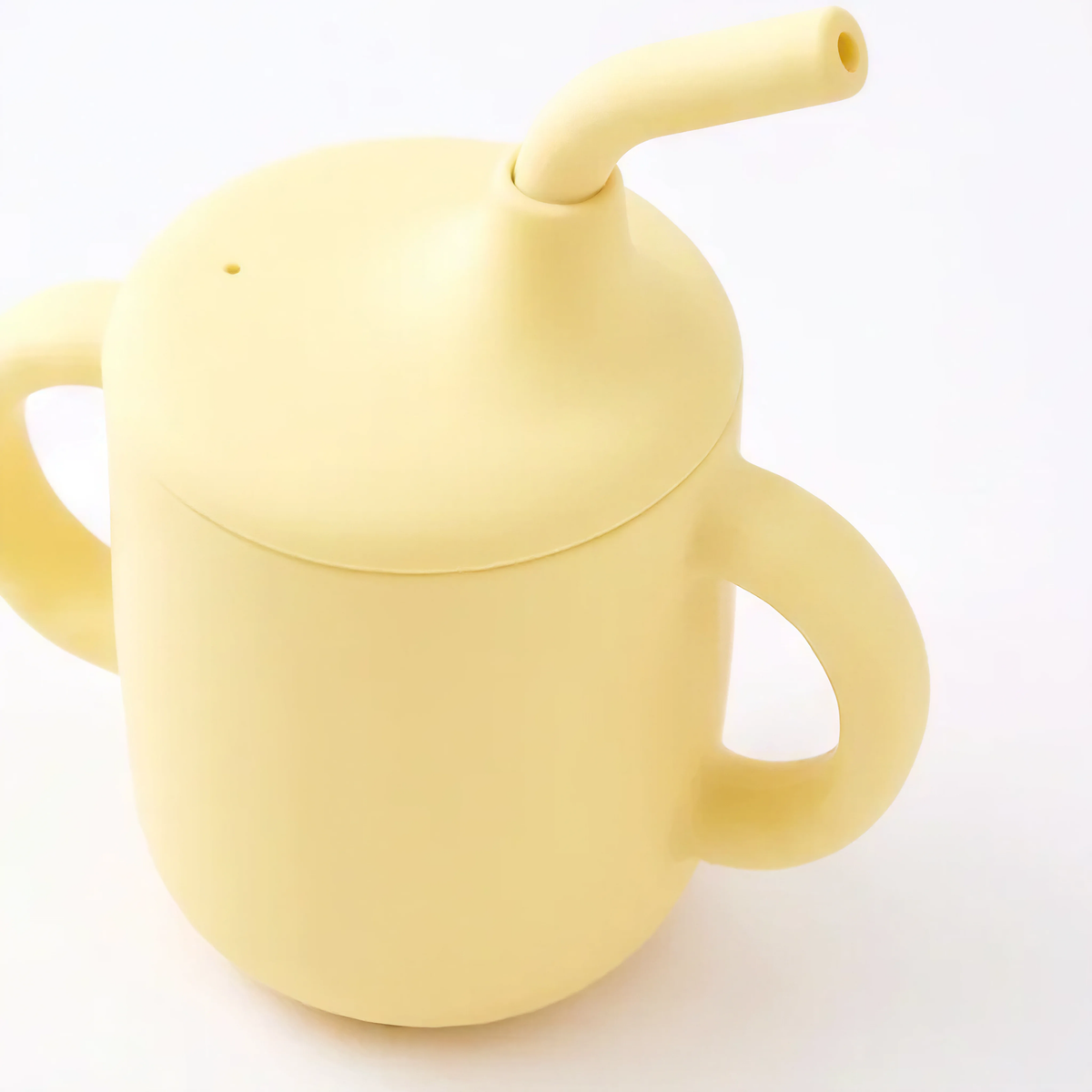 Silicone sippy cup with straw in Dawn (bright yellow), angled view
