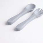 Silicone baby spoon and fork set laid flat, soft-tip ergonomic handles"