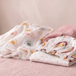Peony Haze muslin swaddle and Sunbeam fitted cot sheet flat lay with minimalist sun print - Honey & Sage