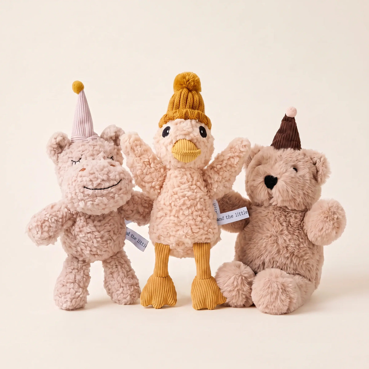 Plush baby soft toys Coco, Jemima and Arthur side by side on a warm backdrop
