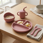 Rosewood pink children's tableware set on a wooden table with food.
